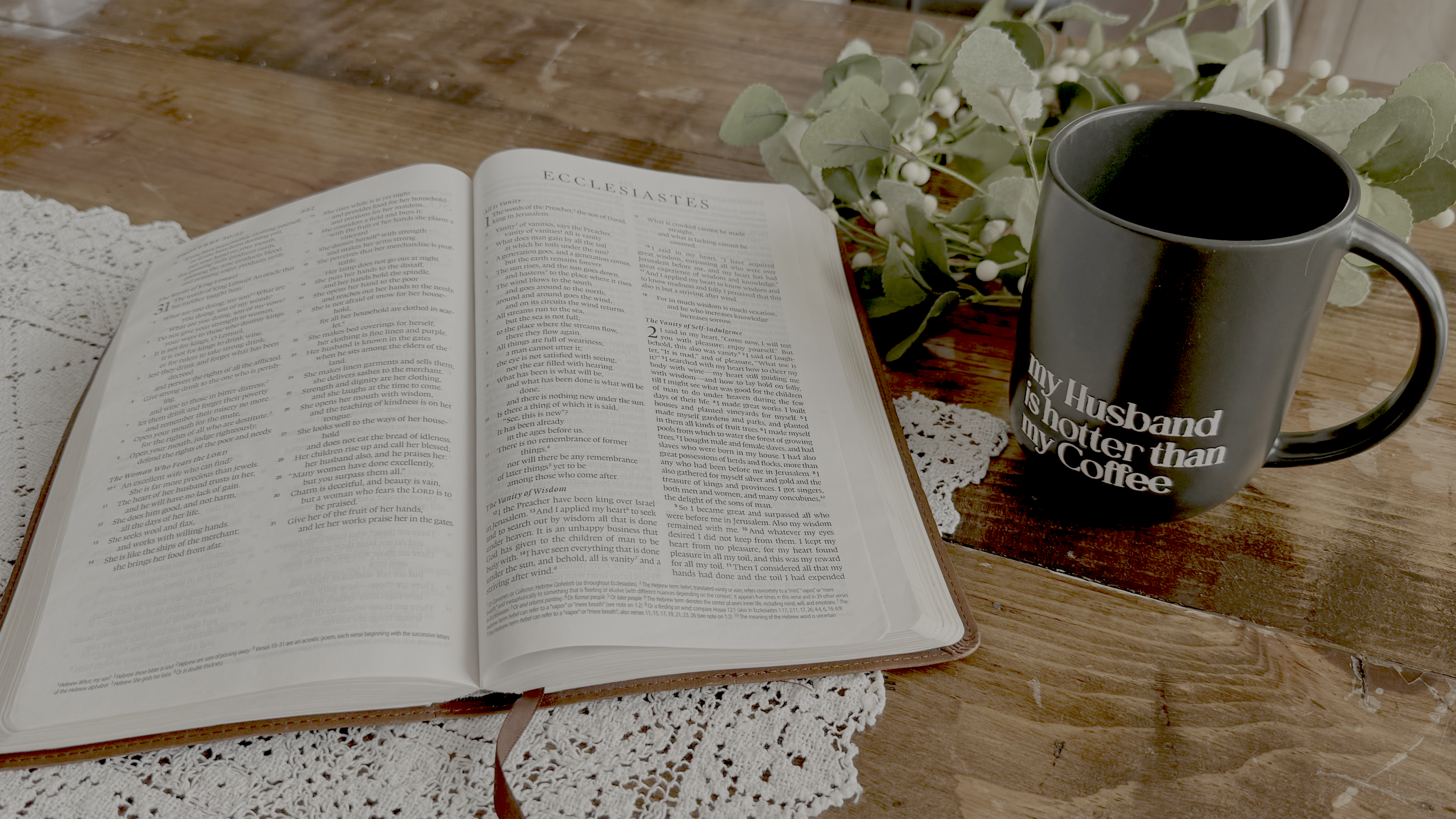 An open Bible beside a mug and eucalyptus branches